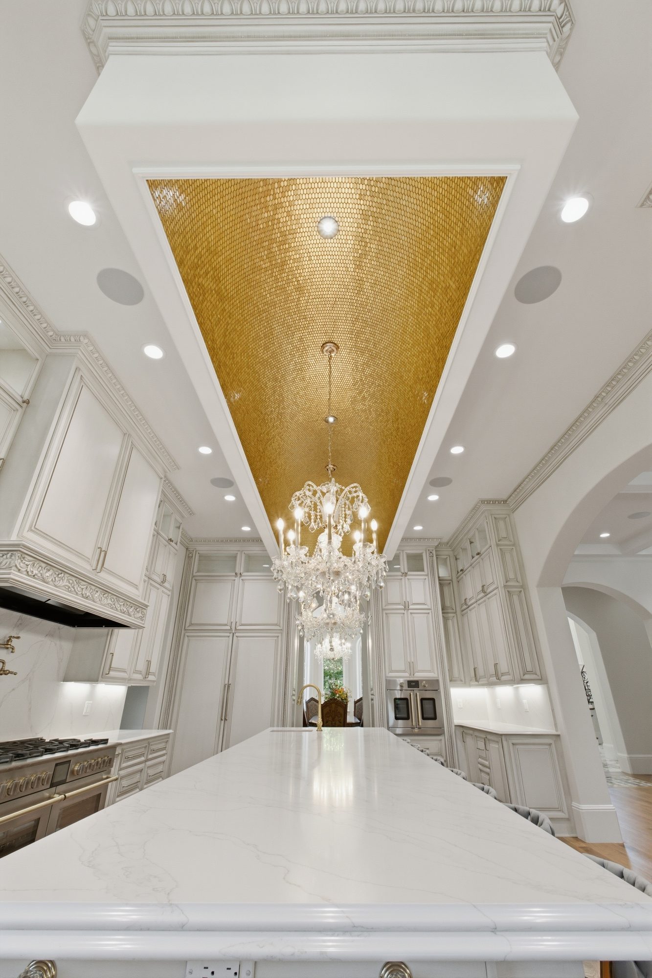 Upward view of the hand-crafted gold mosaic barrel-vault ceiling with crystal chandelier centered beneath